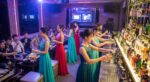 酒吧吧檯前一排身穿禮服的女性調製飲品