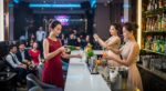 白色吧檯前身穿禮服的女性調製飲品
